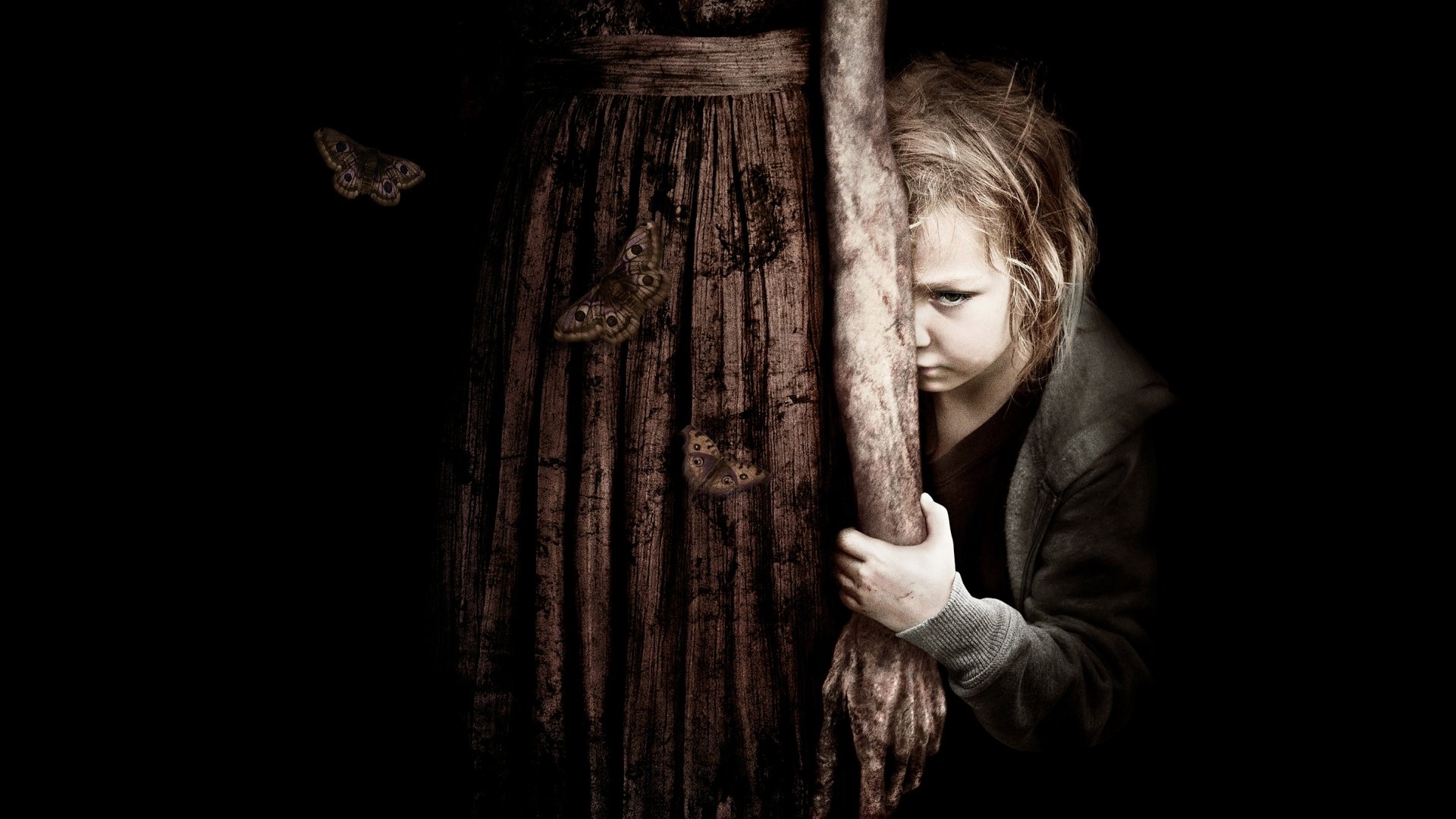 A haunting HD desktop wallpaper from the movie Mama, featuring a child clinging to a ghostly figure, surrounded by dark shadows and fluttering butterflies.