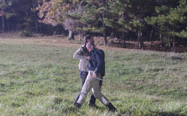 HD desktop wallpaper featuring two characters walking in a grassy field from the TV show The Walking Dead.
