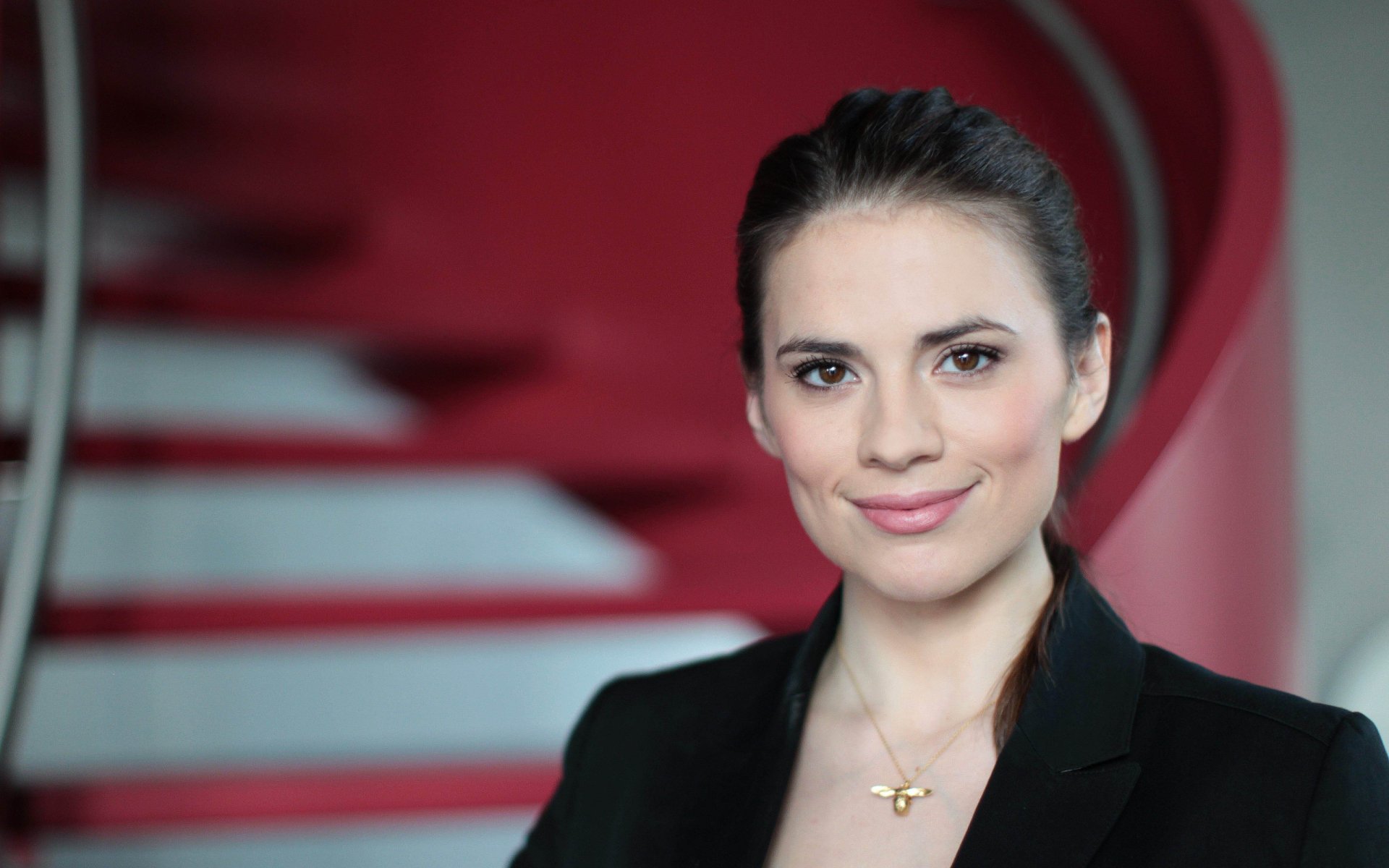HD desktop wallpaper featuring English actress and celebrity Hayley Atwell against a blurred red and white background.