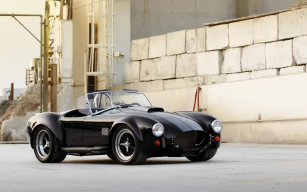 HD desktop wallpaper featuring a sleek black AC Cobra vehicle parked against an urban industrial backdrop.