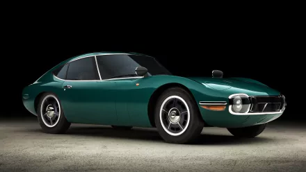 A sleek green Toyota 2000GT sports car, showcased on a dark background, captured in high definition as a desktop wallpaper and background.