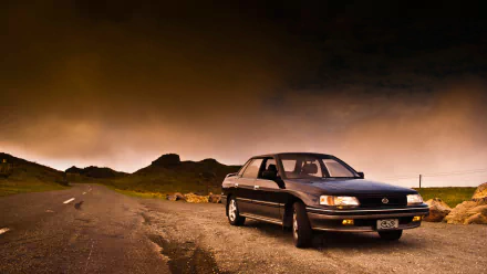Black Subaru Legacy vehicle parked on a remote road under a dramatic sunset sky — HD PC desktop wallpaper/background.
