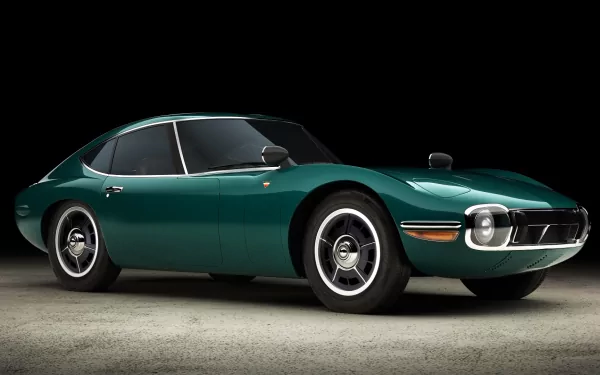 A sleek green Toyota 2000GT sports car, showcased on a dark background, captured in high definition as a desktop wallpaper and background.