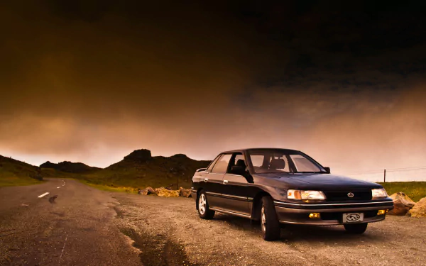 Black Subaru Legacy vehicle parked on a remote road under a dramatic sunset sky — HD PC desktop wallpaper/background.