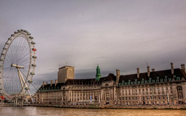 HD desktop wallpaper showing the London Eye and historic riverside buildings under a cloudy sky, highlighting the iconic man-made landmark in London.