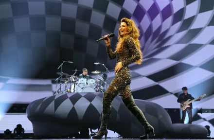 HD desktop wallpaper featuring Shania Twain performing on stage with a dynamic black and white checkered backdrop and band members playing instruments.