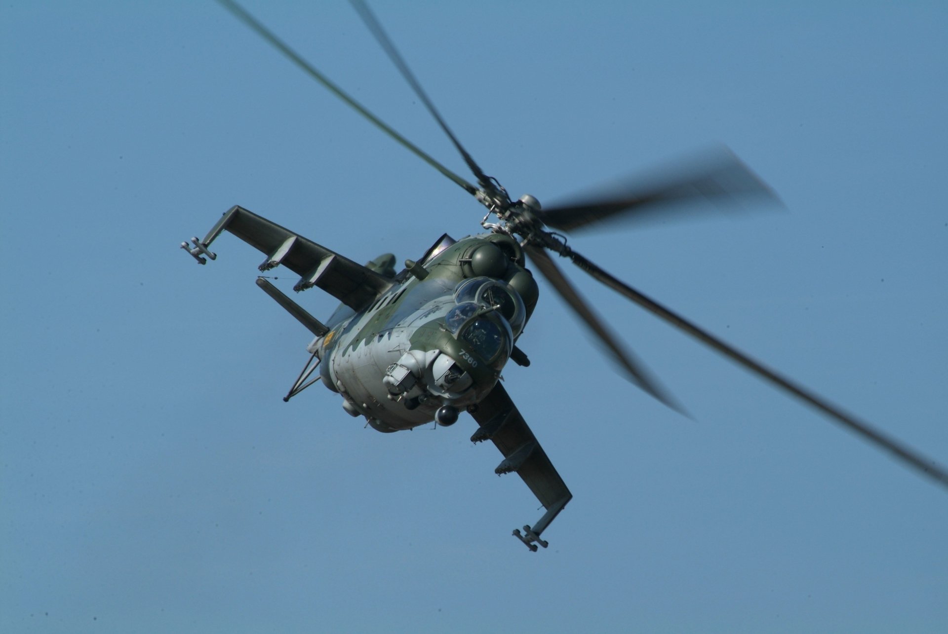 Close-up view of a military Mil Mi-24 helicopter in flight against a clear blue sky, captured in 4K Ultra HD quality for desktop wallpaper.