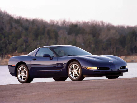 HD PC desktop wallpaper and background: dark blue Chevrolet Corvette (C5) sports vehicle parked by a lakeside with a wooded shoreline behind it.