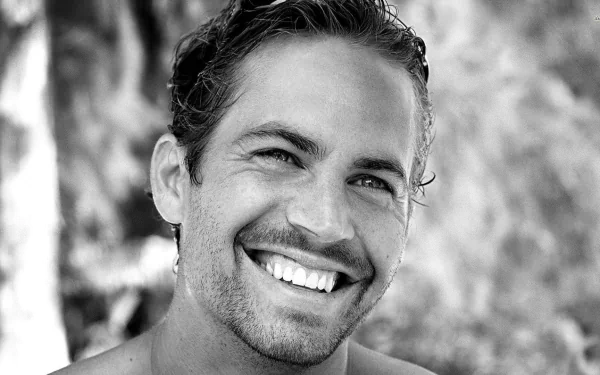 A high-definition desktop wallpaper featuring a charismatic black-and-white portrait of celebrity Paul Walker, showcasing his signature smile and engaging personality.