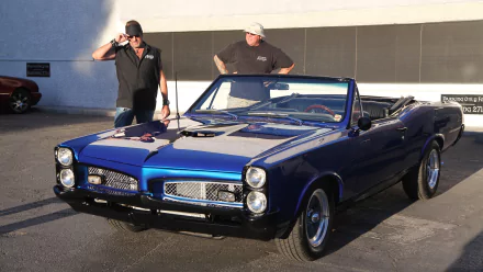 Two men stand beside a classic blue convertible car, featuring sleek lines and chrome details, from the TV show Counting Cars. This image serves as an HD desktop wallpaper and background.
