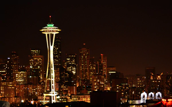 Nighttime view of Seattle’s illuminated Space Needle and surrounding city skyline, captured as a high-definition desktop wallpaper.