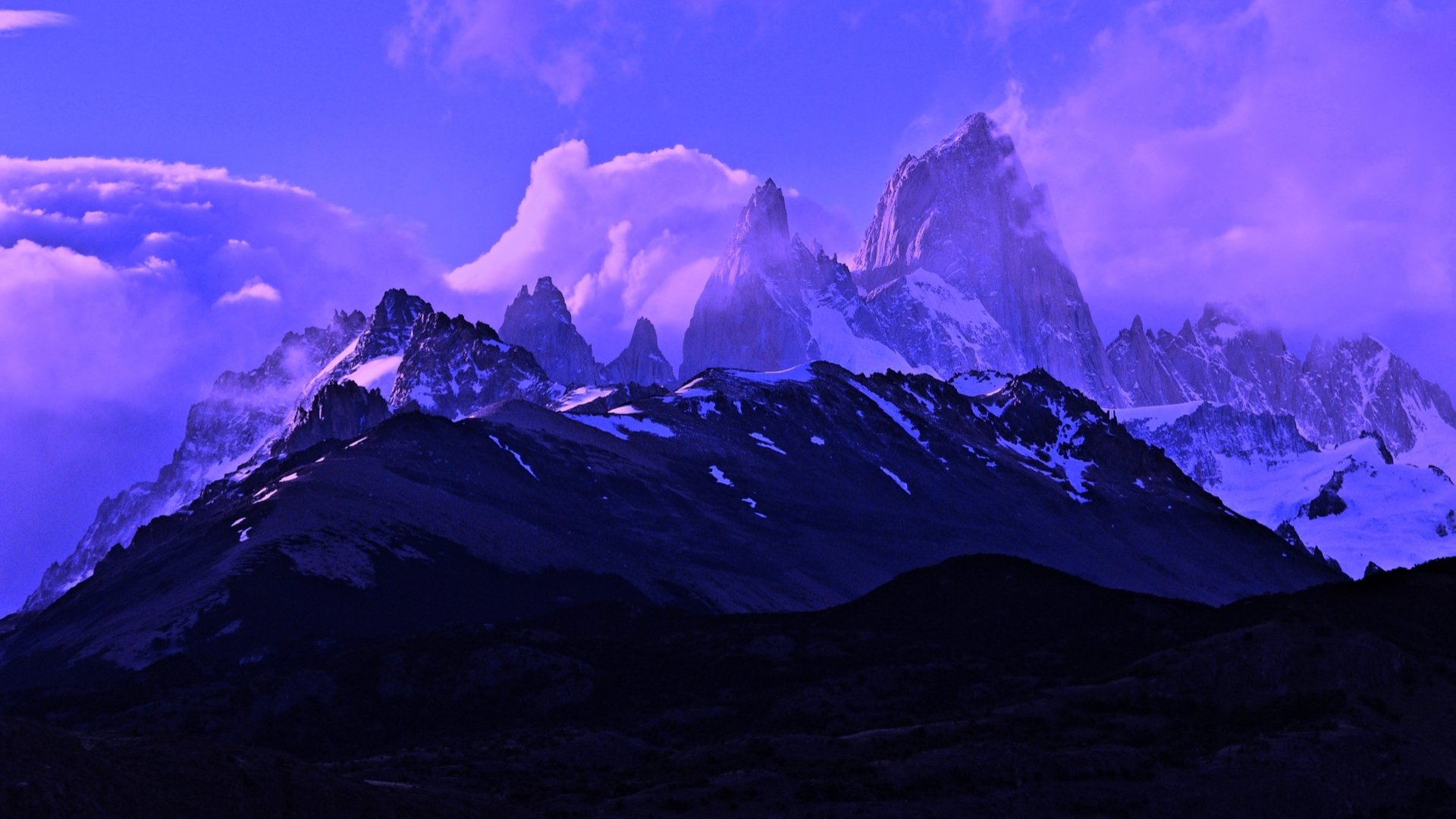 HD desktop wallpaper showcasing Mount Fitz Roy towering above a dark mountain range under a vibrant purple sky in a stunning nature scene.