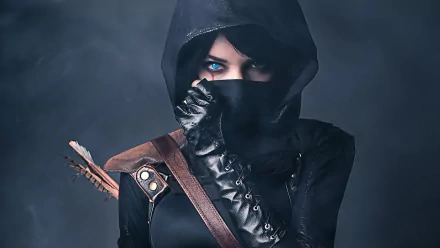 HD wallpaper of a woman in a Thief video game cosplay with a hood, leather glove, and arrow, showcasing blue eyes and a scar.