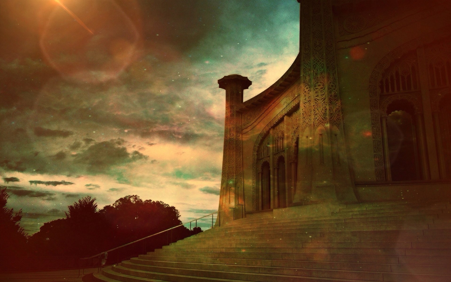 HD PC desktop wallpaper showing a Baha'i temple façade and broad stone steps beneath a dramatic green-orange sunset with light flares.