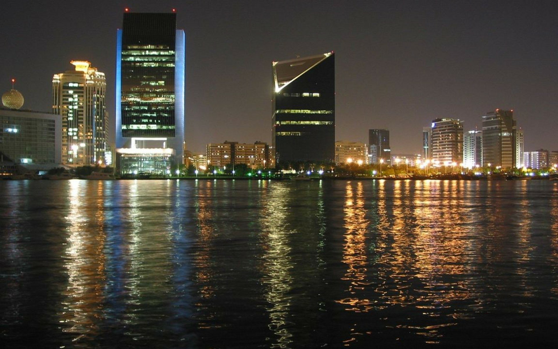 Nighttime view of Dubai's man-made skyline reflecting on calm water, captured as a HD PC desktop wallpaper and background.