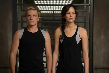 HD desktop wallpaper featuring characters from The Hunger Games: Catching Fire movie, showcasing their determined expressions in a dimly lit setting.