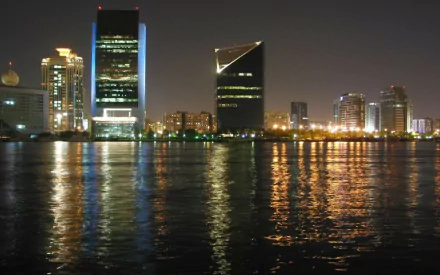 Nighttime view of Dubai's man-made skyline reflecting on calm water, captured as a HD PC desktop wallpaper and background.