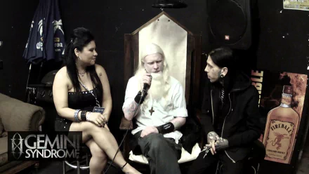 HD desktop wallpaper featuring three people in a casual interview setting, with the Gemini Syndrome logo displayed.