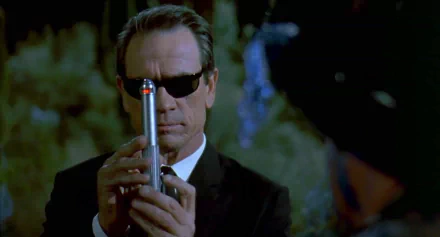 HD PC desktop wallpaper featuring a scene from the movie Men In Black, showing a man in sunglasses holding a futuristic device.