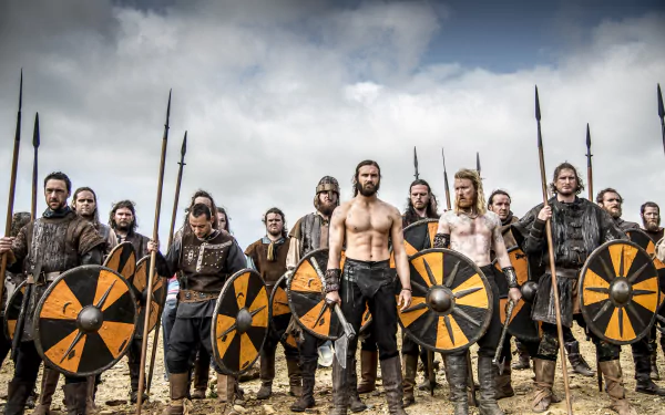 HD desktop wallpaper from Vikings (2013) TV show featuring Rollo and warriors holding round shields in a battle-ready stance under a cloudy sky.