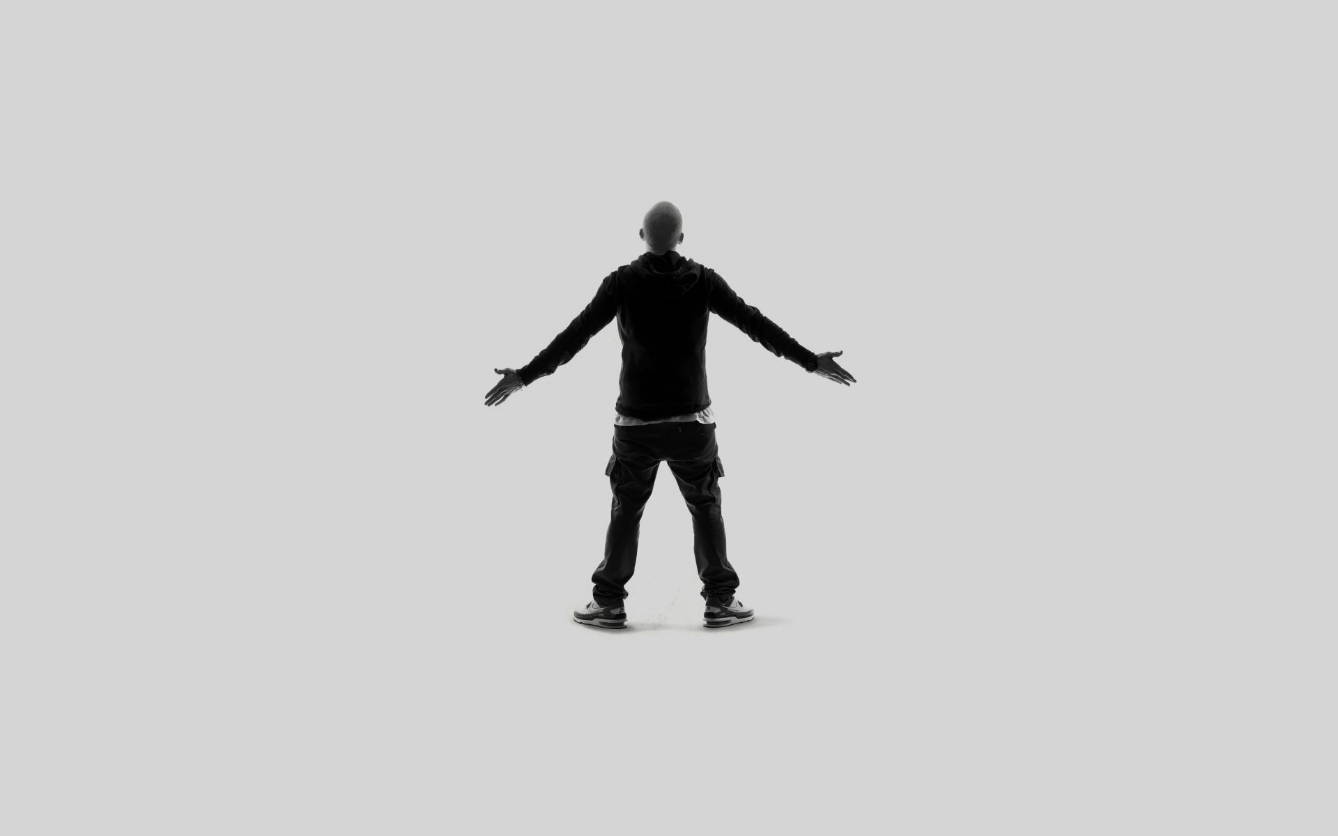 A silhouette of a man with arms outstretched, set against a minimalist background, serves as a striking HD desktop wallpaper celebrating the essence of music, inspired by Eminem.