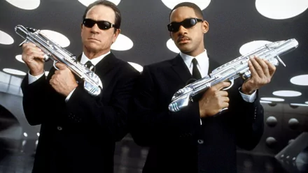HD PC desktop wallpaper featuring Men In Black 3 movie scene with two agents in black suits and sunglasses holding futuristic weapons.