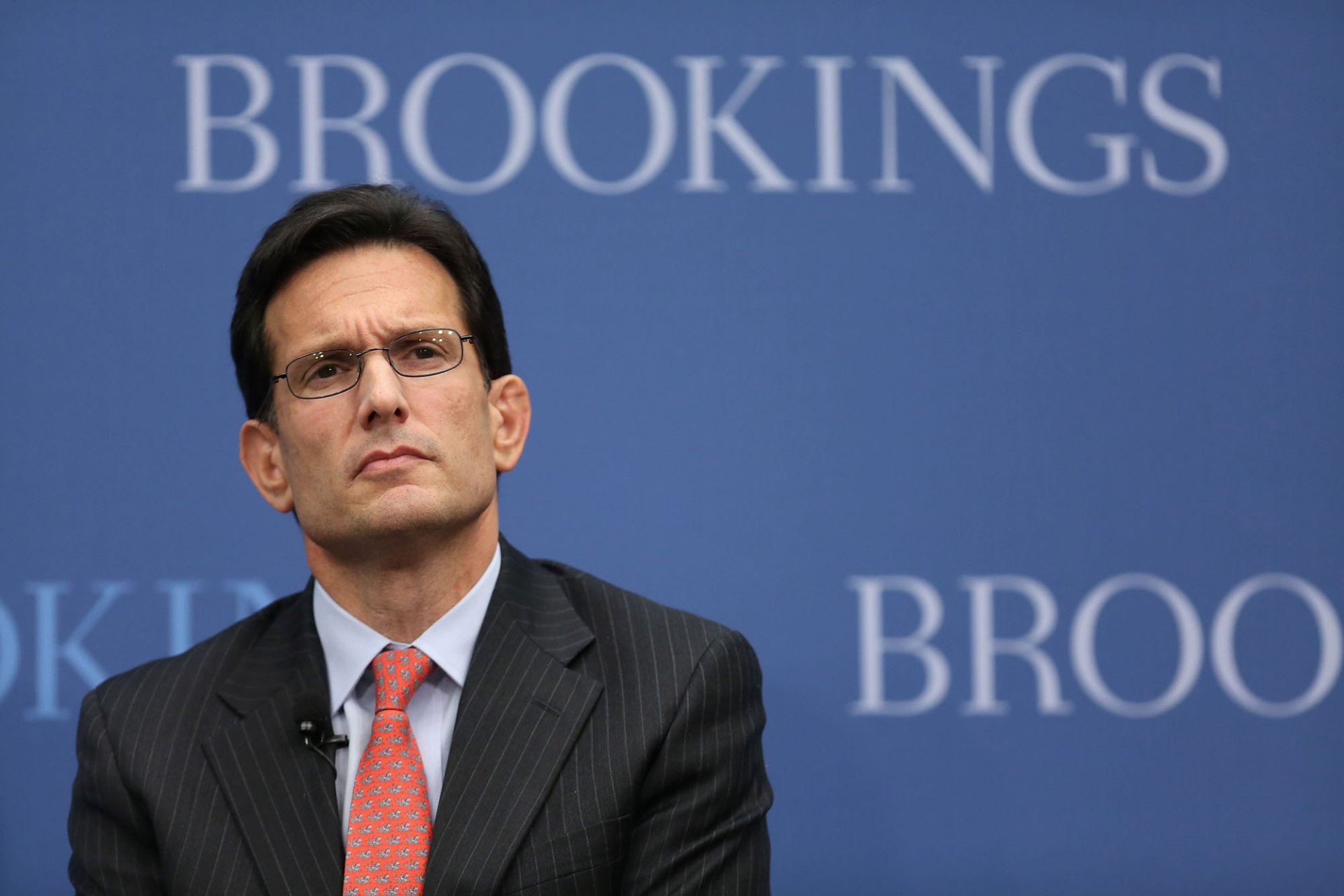 HD desktop wallpaper featuring a man in a suit against a background with the word BROOKINGS visible.