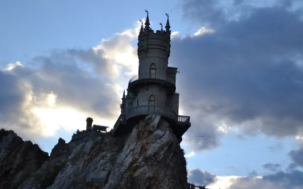 Swallow's Nest, a man-made castle perched on a cliff overlooking the sea in Yalta, Russia, captured against a dramatic cloudy sky.