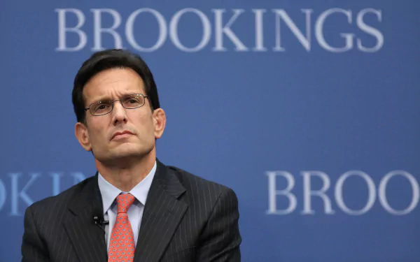 HD desktop wallpaper featuring a man in a suit against a background with the word BROOKINGS visible.