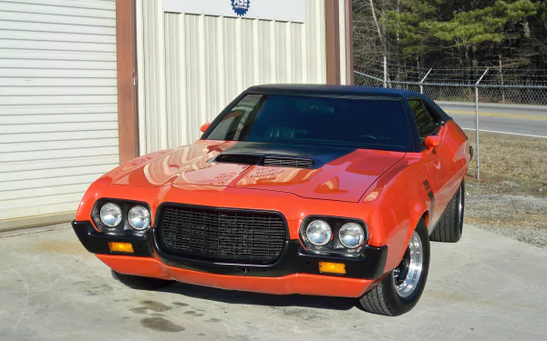 Red Ford Gran Torino Sport parked by a garage, glossy hood, black grille and chrome wheels in sunlight — 4K Ultra HD PC desktop wallpaper and background.