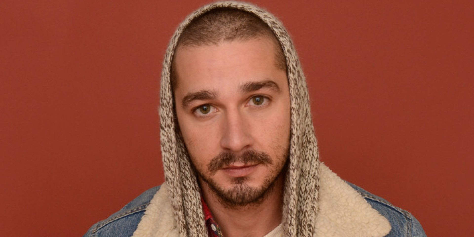 HD wallpaper of a person with a hoodie in a denim jacket against a maroon background, serving as a desktop backdrop.