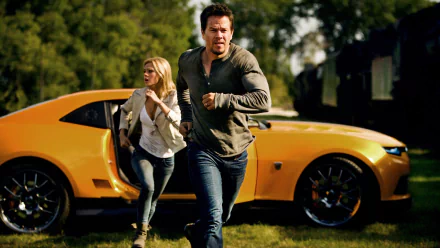Mark Wahlberg and a woman run away from a yellow car in a scene from *Transformers: Age of Extinction*, showcasing an intense moment from the movie. HD desktop wallpaper.
