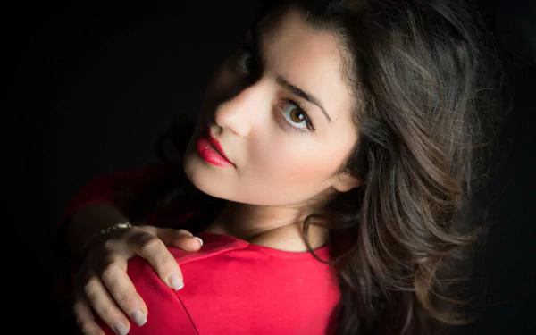 A close-up of a woman in a red top, featuring her face and soft curls. The HD image serves as an elegant desktop wallpaper or background.