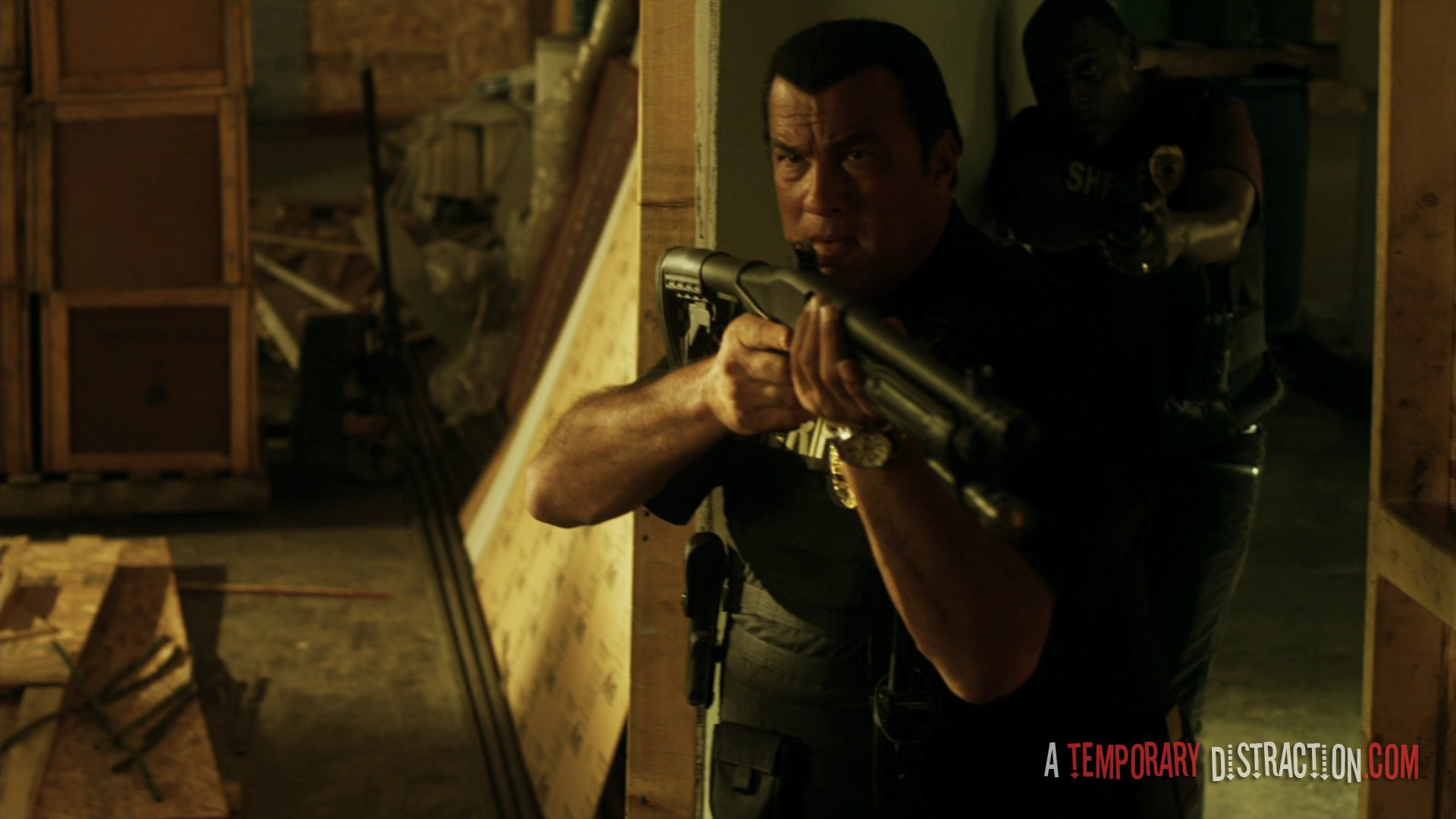 HD PC desktop wallpaper: True Justice movie True Justice: Deadly Crossing scene — armed officer aims a shotgun in a dim warehouse, caption reads A Temporary Distraction.