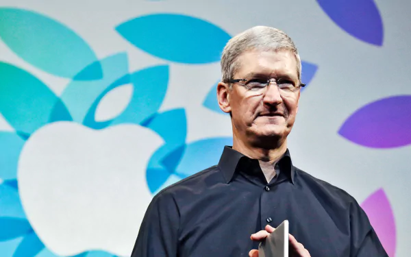 A man in black standing in front of a colorful Apple logo, formatted as a high-definition desktop wallpaper.