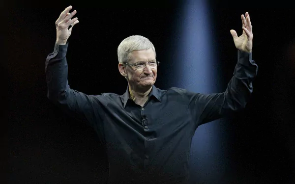 A man in a black shirt gestures on stage, serving as a high-definition desktop wallpaper and background.