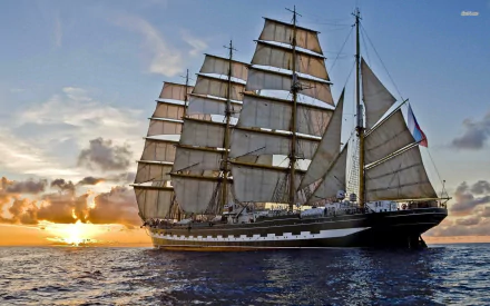 A majestic tall ship with billowing sails glides through calm waters at sunset, showcasing its grandeur as a stunning HD desktop wallpaper and background.