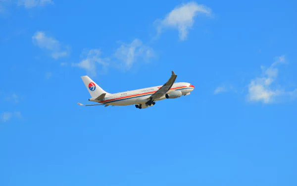 An Airbus A330 passenger plane from China Eastern Airlines soars through a bright blue sky, creating a striking HD desktop wallpaper background.