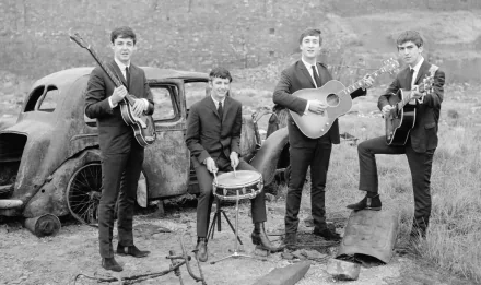 Black and white HD desktop wallpaper featuring The Beatles posing with instruments near an old car, capturing the essence of their iconic music and style.