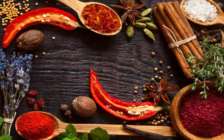 Vibrant herbs and spices including chili peppers, cinnamon sticks, star anise, and ground powders arranged on a dark wooden surface, captured in HD for a PC desktop wallpaper.