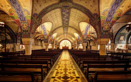 Interior view of the ornate Basilica of St. Thérèse in Lisieux, showcasing its colorful arches and patterned floor in an HD PC desktop wallpaper.