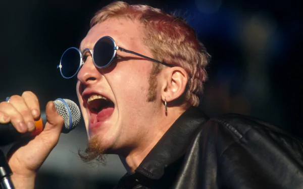 HD desktop wallpaper of a singer from Alice In Chains passionately performing with round sunglasses and a microphone.