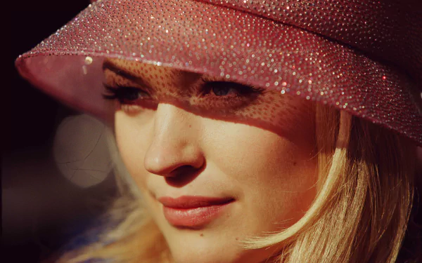 Close-up of actress Sophia Myles, wearing a sparkling pink hat, showcasing her elegant features in a soft, warm light. This HD wallpaper captures her celebrity charm beautifully.