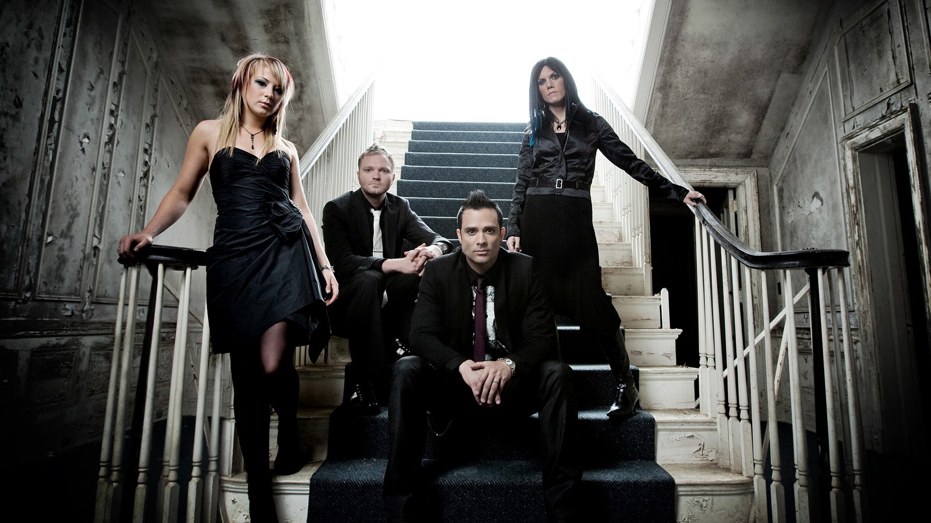 HD PC desktop wallpaper featuring the rock band Skillet posing on a stairway in a dim, industrial setting.