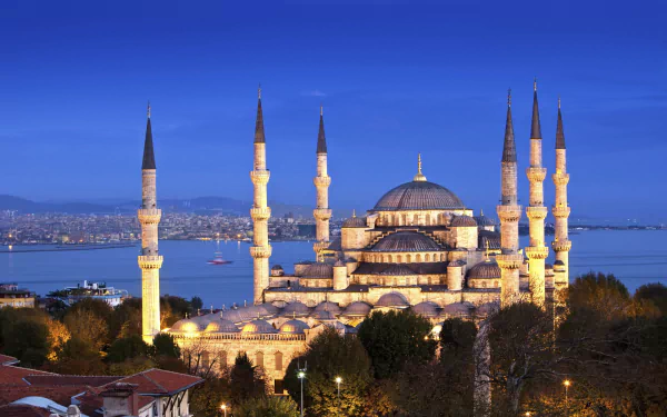 A stunning HD wallpaper of the Sultan Ahmed Mosque, showcasing its majestic domes and towering minarets against a twilight sky, set by the serene waters of Istanbul.