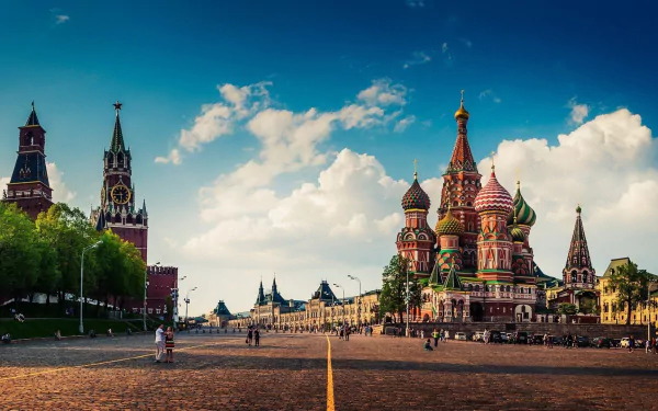 A vibrant HD desktop wallpaper showcasing Moscow's iconic architecture, featuring St. Basil's Cathedral and the Kremlin under a clear blue sky with fluffy clouds.