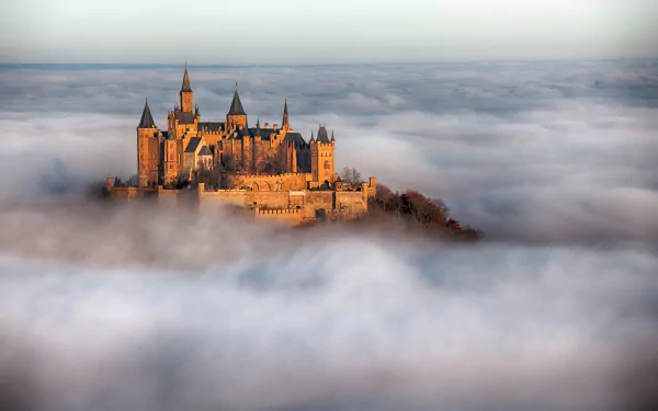 A stunning HD wallpaper of Hohenzollern Castle emerging from a sea of clouds, showcasing the enchanting blend of man-made architecture and natural beauty.