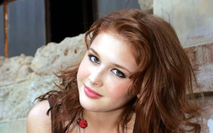 HD desktop wallpaper of American actress Renee Olstead, featuring a close-up of a woman with wavy auburn hair and a slight smile, set against a rustic background.