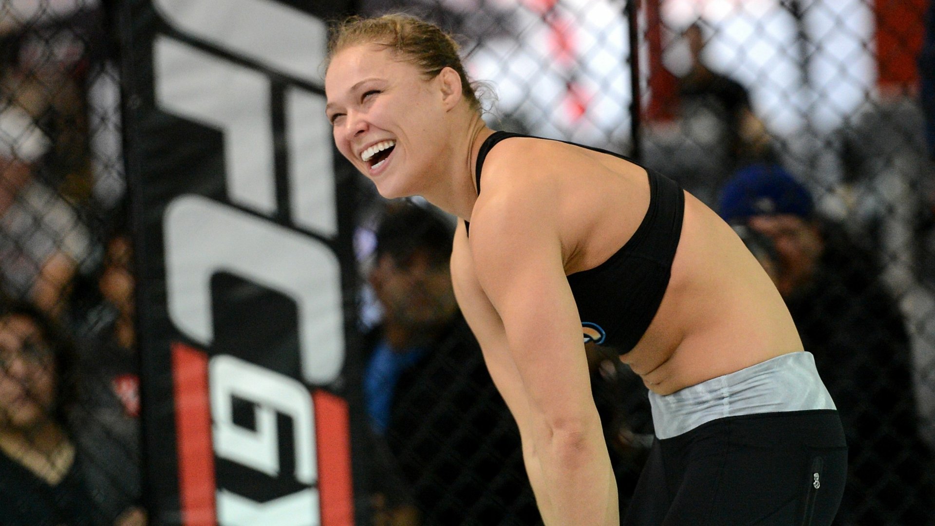Ronda Rousey smiles during a training session, showcasing her athletic spirit. This HD wallpaper captures her dynamic presence in the sports world.
