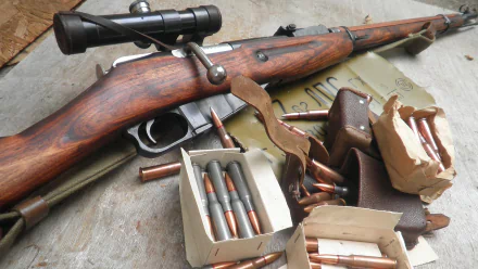 HD PC desktop wallpaper/background showing a man-made Mosin Nagant rifle with scope, boxes of ammunition and loose rounds arranged on a weathered surface.